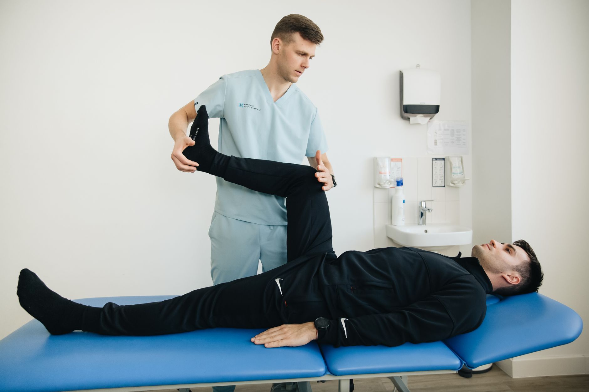 Kỹ thuật viên hỗ trợ người bệnh kéo giãn chân trên bàn tập